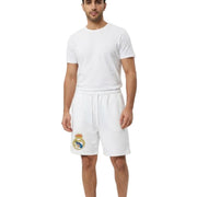 A man modeling a white short-sleeve t-shirt and matching white shorts with the Real Madrid crest on the left leg, set against a plain white background.