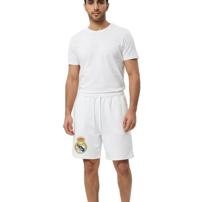 A man modeling a white short-sleeve t-shirt and matching white shorts with the Real Madrid crest on the left leg, set against a plain white background.